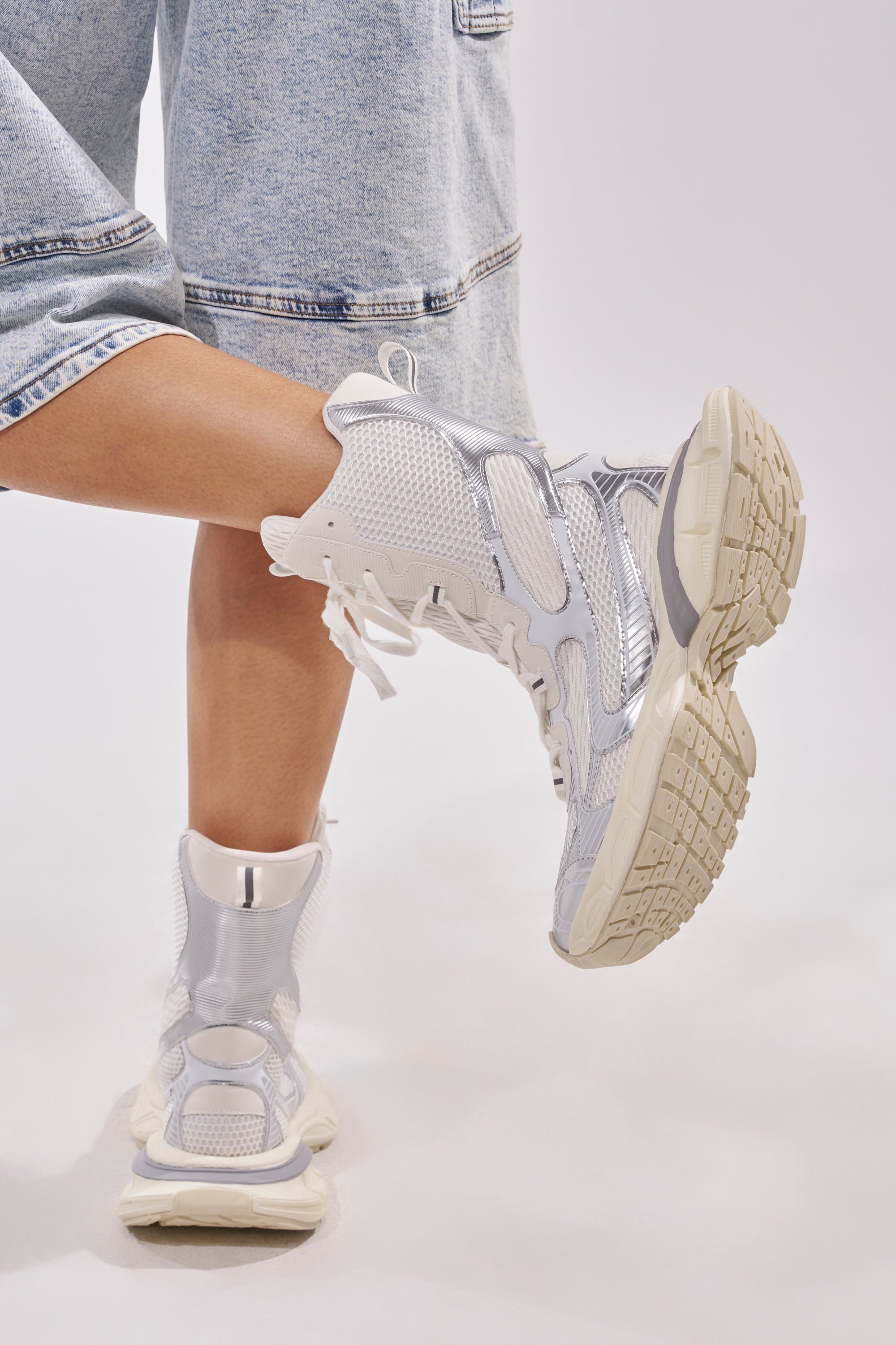 A person stands with one leg crossed behind the other against a plain light background, wearing light denim shorts and AZALEA WANG YVONNE WHITE LACE UP SNEAKER. 2
