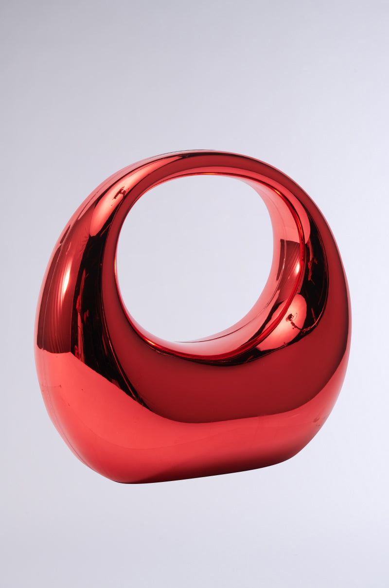 Introducing the "CHERRY ON TOP CHROME PURSE" — a stylish, contemporary accessory with a glossy red exterior and shimmering chrome accents. Its unique oval shape and open center design create an intriguing hollow effect, while the flawless surface shines brightly, subtly mirroring light and its surroundings. 3