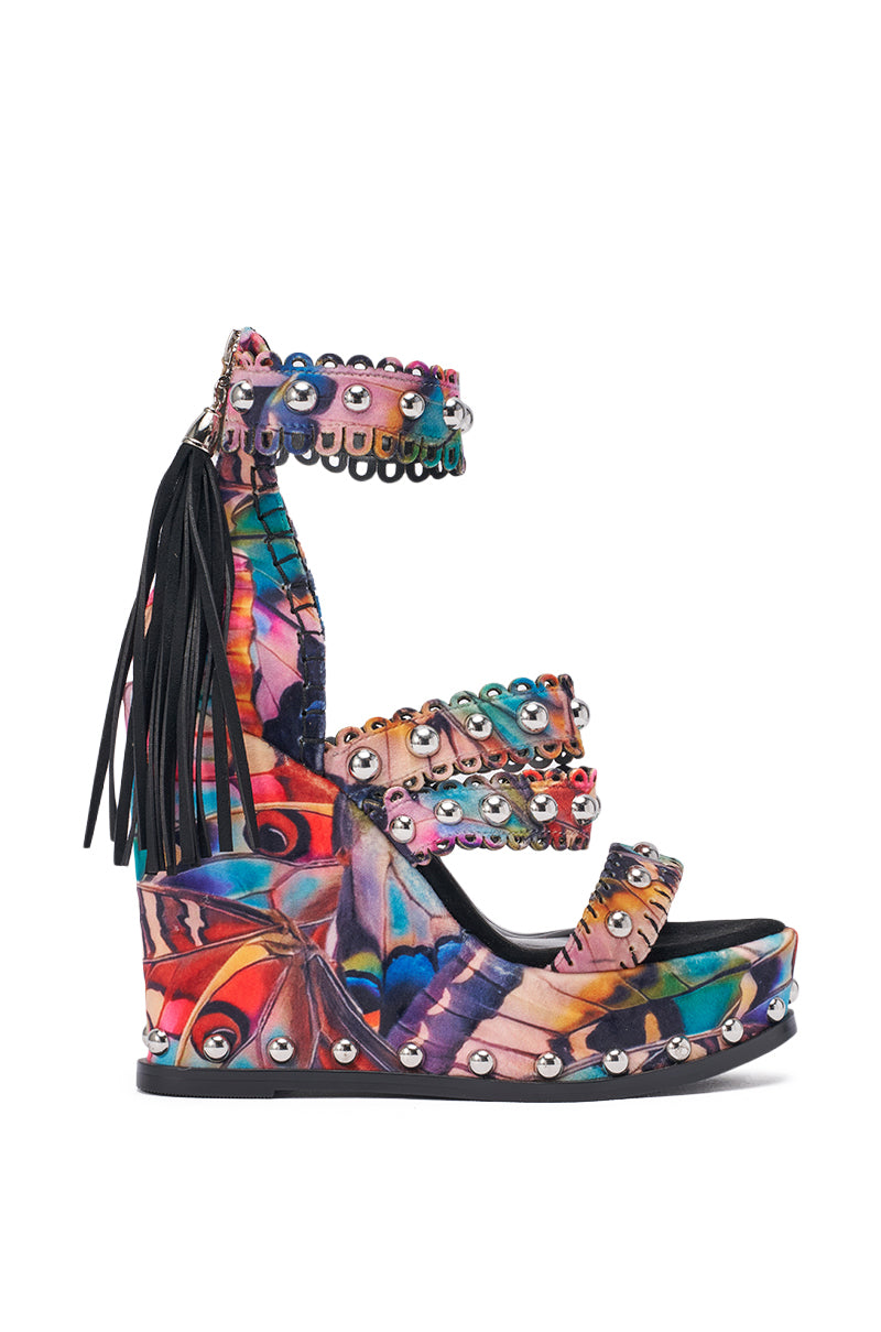 The AKIRA GOLD ZANIA BUTTERFLY MULTI PRINT FRINGE EMBELLISHED WEDGE SANDAL features a bold multicolor abstract pattern, four studded straps with silver rivets, black fringe accents, and a comfort cushion insole for stylish support. 4
