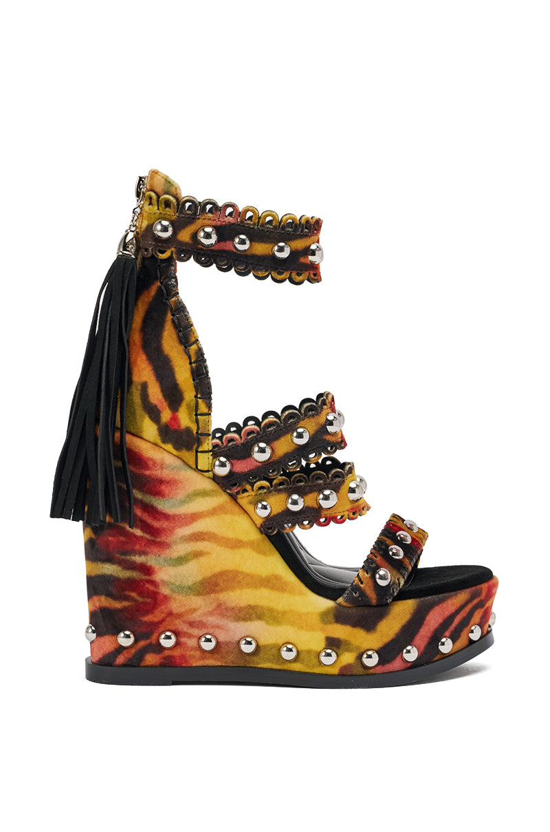 The AKIRA GOLD ZANIA TIGER MULTI PRINT FRINGE EMBELLISHED WEDGE SANDAL features a bold orange, yellow, and black tiger print, multiple studded straps, a heel zipper with tassel, and silver studs along the sole. 4