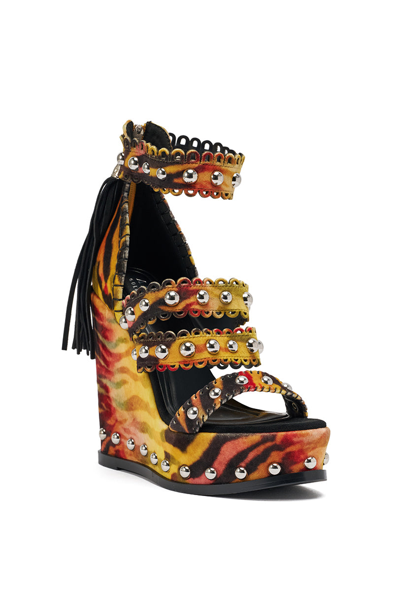 The AKIRA GOLD ZANIA TIGER MULTI PRINT FRINGE EMBELLISHED WEDGE SANDAL features a high wedge, yellow/orange/black tiger print, studded straps, scalloped edges, ankle strap, metallic studs, and black fringe detailing on the back. 5