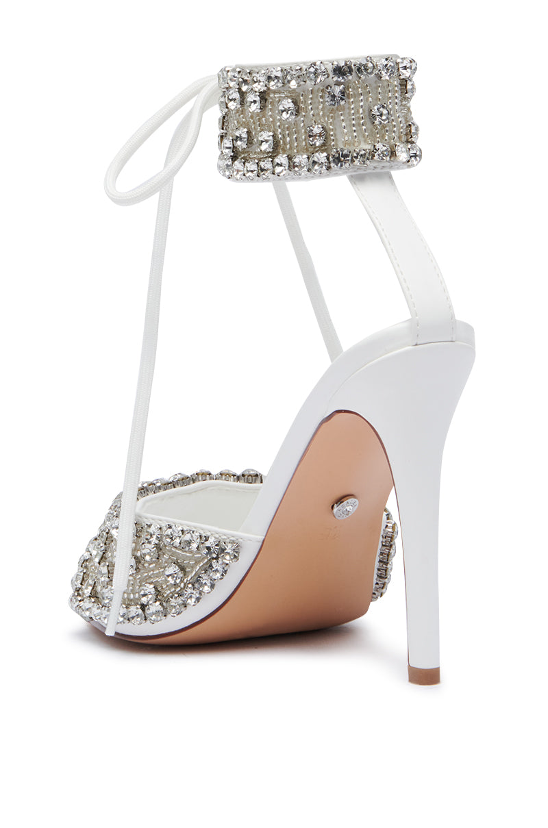 The AZALEA WANG ZELANIA WHITE SANDAL is a high-heeled faux leather sandal featuring a white sole and tan underside, adorned with sparkling silver rhinestones on the toe strap and ankle strap. It includes a wrap-around lace detail, and its slender stiletto heel adds elegance while the comfort cushion insole ensures all-day wearability.