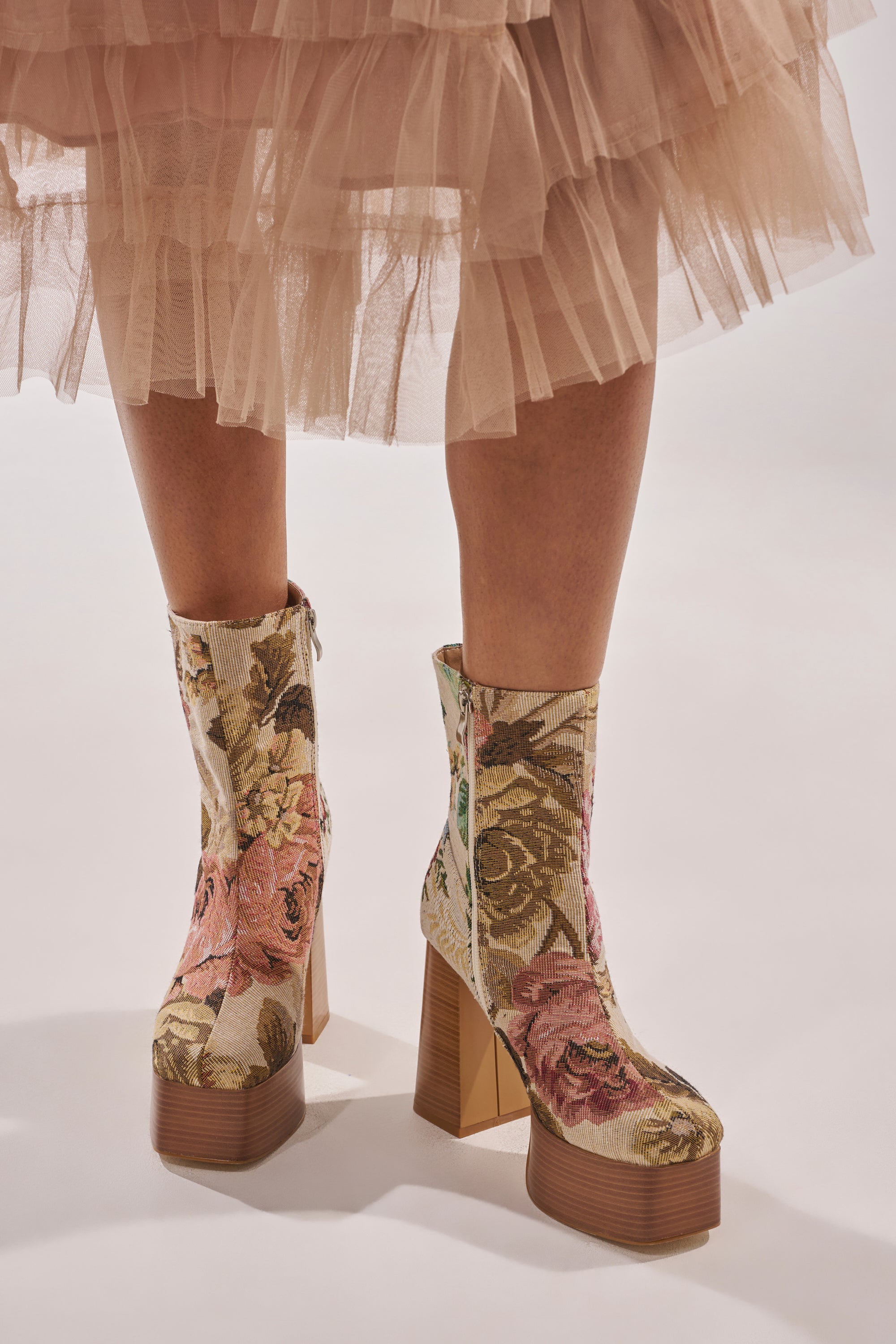 A person wearing a beige tulle skirt and AZALEA WANG ZILPAH FLORAL BROCADE BOOTIE stands on a light surface. 2