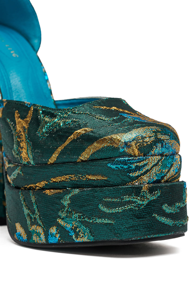 Close-up of the AZALEA WANG ZIPPHORA BLUE BROCADE CHUNKY PUMP, a vintage-inspired platform heel in teal and gold patterned fabric with an open toe and shimmering embroidered designs.