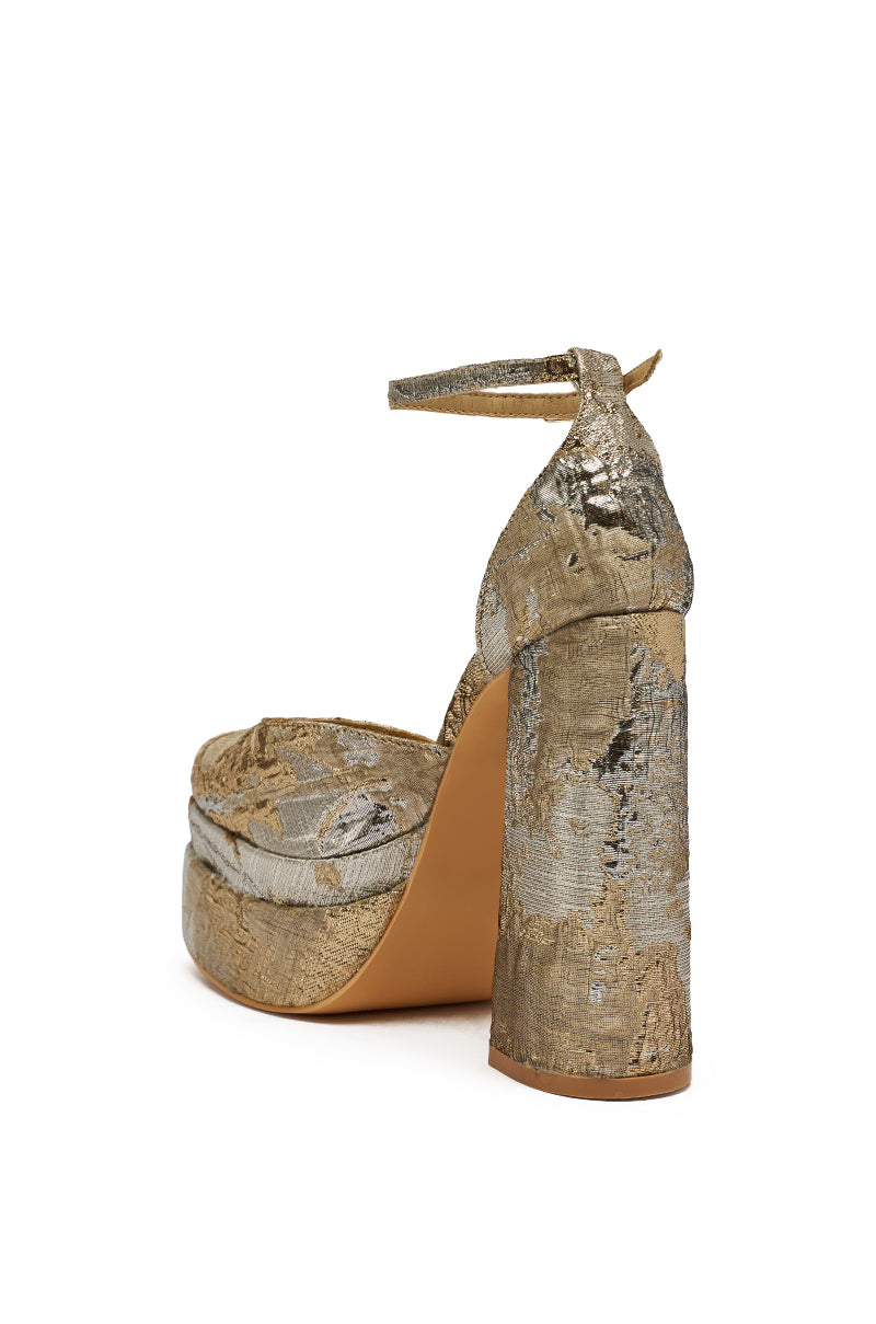 The AZALEA WANG ZIPPHORA GOLD MULTI BROCADE PLATFORM PUMP features a gold and silver brocade, chunky block heel, ankle strap, and closed back, displayed from a rear side angle against a white background. 5