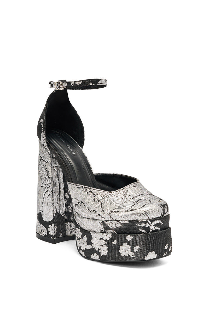 The AZALEA WANG ZIPPORAH BLACK BROCADE PUMP features a platform sole, chunky heel, ankle strap, and an elegant silver floral brocade pattern covering the entire black shoe.