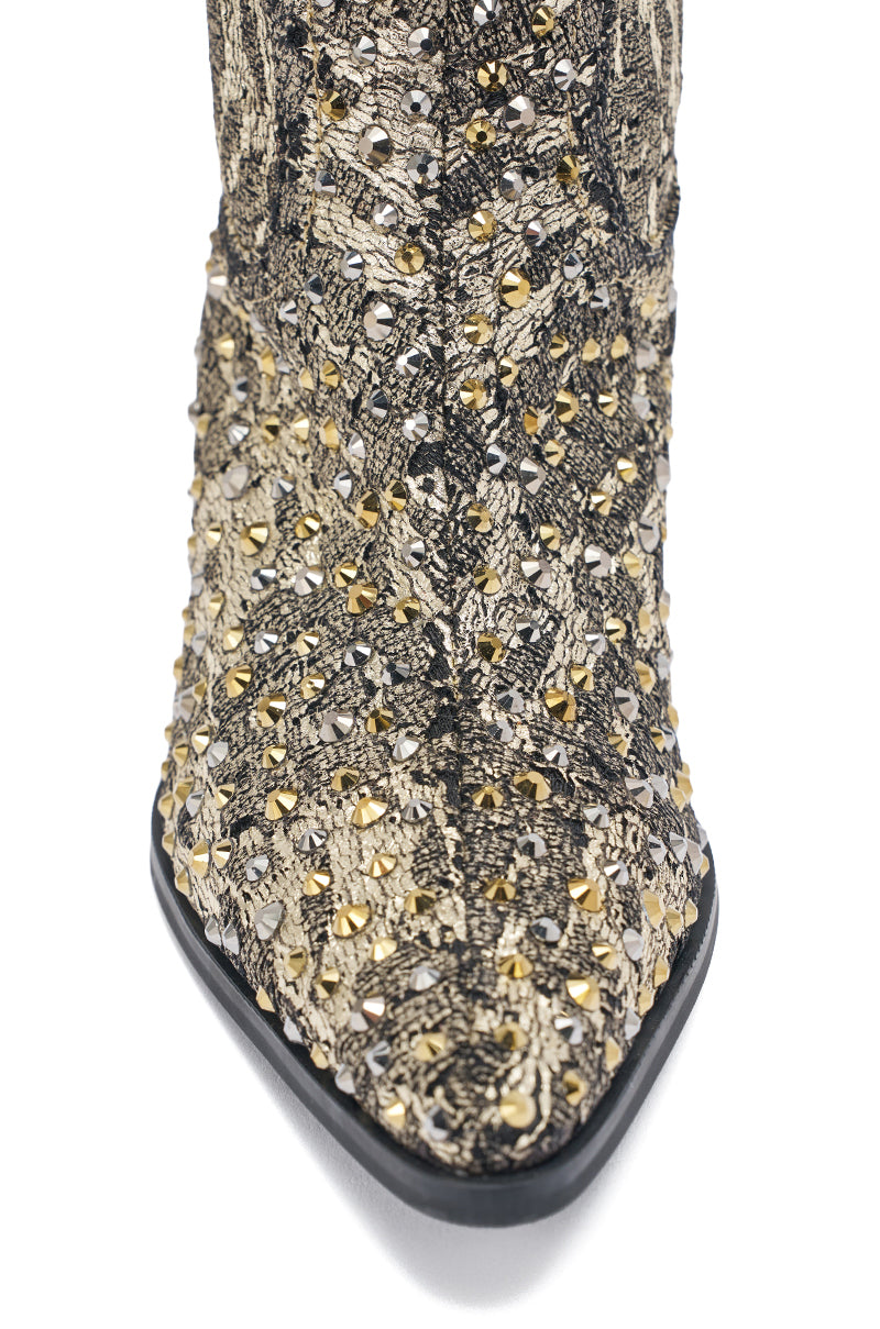 Close-up of the AZALEA WANG ZIRENNE GOLD AND BLACK BROCADE WESTERN BOOT, featuring a pointed toe, woven fabric, rhinestone embellishments in gold and silver, and a contrasting black sole.