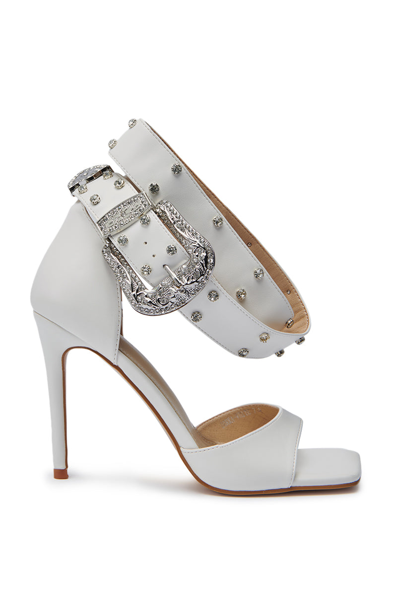 The AZALEA WANG ZORKA WHITE WESTERN BUCKLE STILETTO SANDAL is a white, open-toe sandal adorned with rhinestones and a large crystal buckle on the ankle strap. 3