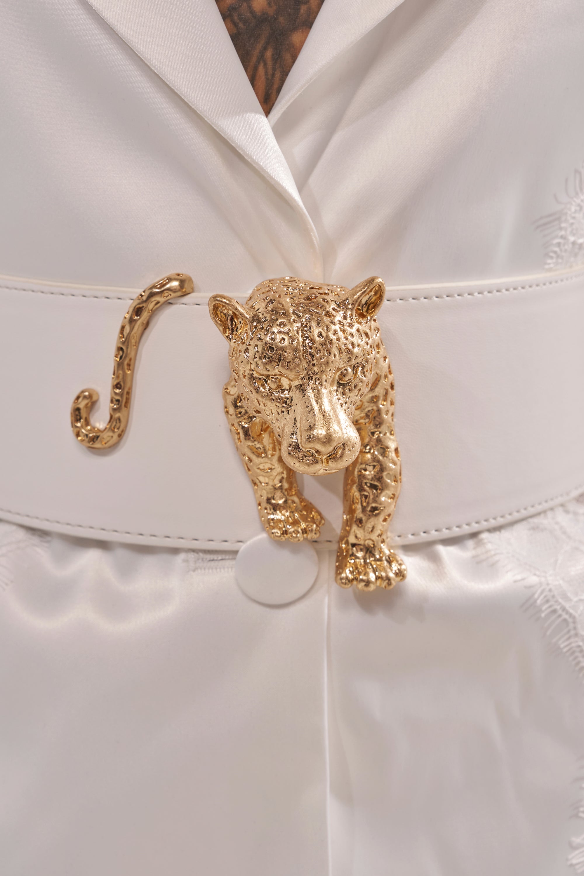 Close-up of the NO BOUNDARIES PU STRETCH BELT IN WHITE, a wide faux leather belt with a gold leopard-shaped buckle, featuring its body and tail extending from the center. 2