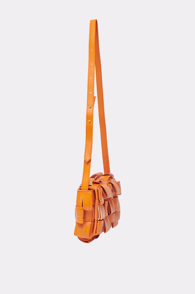 The ORANGE YOU GLAD? PURSE is a faux leather crossbody bag with a long adjustable strap and a ruffled body, shown against a plain light background.