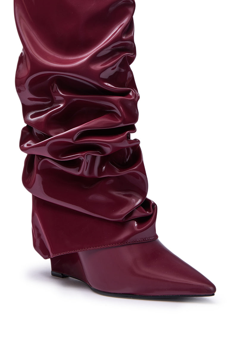 Close-up of the AZALEA WANG ZYLLA Burgundy Patent Wedge Ruched Boot, featuring a glossy knee-high silhouette with a pointed toe and ruched design in shiny burgundy patent leather.