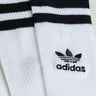 Close-up image of a pair of SEXY HOSIERY INTIMATE white socks by Adidas, featuring black horizontal stripes near the top and the Adidas trefoil logo with the word "adidas" embroidered below it. The socks have a ribbed texture.