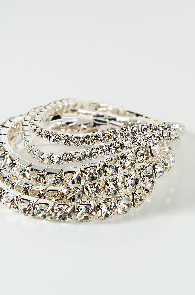 A close-up shot of the BRACELET SILVER, showcasing its sparkling rhinestone details. This bracelet features multiple rows of silver-colored settings adorned with clear, faceted rhinestones that catch the light, creating a dazzling effect. The design is elegant and intricately crafted.