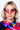 A woman with blonde hair wearing angular pink BAT WING SUNNIES and large, colorful, beaded hoop earrings. She has pink eye shadow and a colorful, abstract-patterned shirt with a mix of red, blue, yellow, and green hues. The background is plain white.