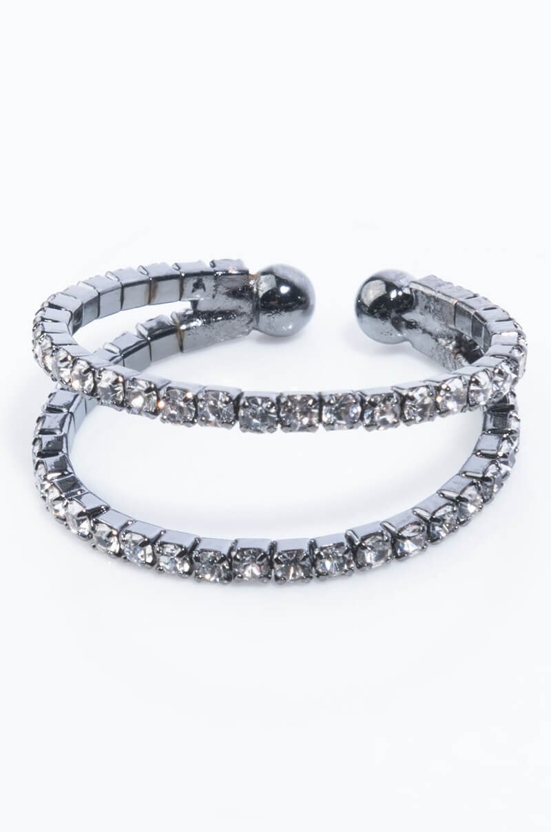 Two sleek gold-toned rings, named the BETSY RING GOLD, are stacked against a white background. Both rings are adorned with sparkling, clear rhinestones, enhancing their elegance. The bands are slightly open-ended, giving them a stylish, modern appearance.