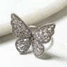 Close-up image of the BRATZ DOLL BUTTERFLY RING, designed in the shape of a butterfly. The butterfly wings are embellished with an array of small, sparkling gemstones arranged in a structured, intricate pattern. The background is a smooth, white surface.