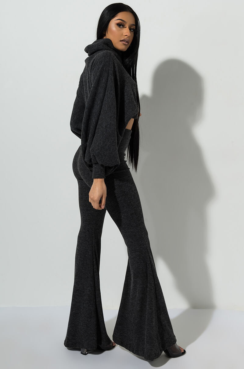 A person wearing the SEXY FASHION PANT in heather gray stands against a plain light-colored background. The two-piece outfit features a high-neck, long-sleeved top and flared pants. They have long, straight black hair and are posing with their head turned slightly to the side.