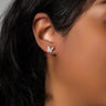 Close-up image of a person wearing a RM Manufacturing silver butterfly-shaped EARRING. Only their ear, part of their cheek, and black hair are visible. The background is neutral, emphasizing the earring.