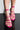 Close-up of a person wearing the MAMA CAN I GET AN AMEN CHUNKY STRAPPY SANDALS in bright pink, featuring multiple thin straps wrapped around their feet and ankles. The sandals have open toes, showcasing the person’s neatly manicured toenails. The reflection of the sandals and feet is visible on a shiny surface.