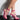 A pair of feet are adorned with the MAMA CAN I GET AN AMEN CHUNKY STRAPPY SANDAL, featuring pink straps and clear wedge heels. The wearer stands on a glossy black surface against a white background, showcasing the multiple straps that wrap elegantly around their ankles and feet.