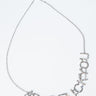 A silver chain necklace spells out "ABCDEFUCKYOU" in glittering letters and is laid out flat against a white background.