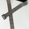 The DIAMANTE RHINESTONE BELT, showcasing a grey and black fabric with a metallic sheen, is laid flat on a white surface. It features multiple holes for adjustment and is complemented by a rectangular metal buckle.