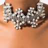 Close-up of a person wearing the LYNNKA Rhinestone Pearl Choker, adorned with clusters of pearls and sparkling rhinestones, arranged in a symmetrical pattern. The design features intricate, flowing shapes and adds a touch of elegance and glamour to the neckline.