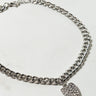 A HEART OF GOLD CHAIN ANKLET SILVER with a heart-shaped pendant adorned with small, sparkling stones, lying on a light-colored surface.