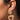 Close-up of a person's ear adorned with the HANA TEXTURE EARRING, featuring a golden, textured stud and a larger triangular, open pendant hanging below. The intricate and shimmering details are beautifully showcased against the person's smooth skin and pulled-back hair, highlighting the earring.