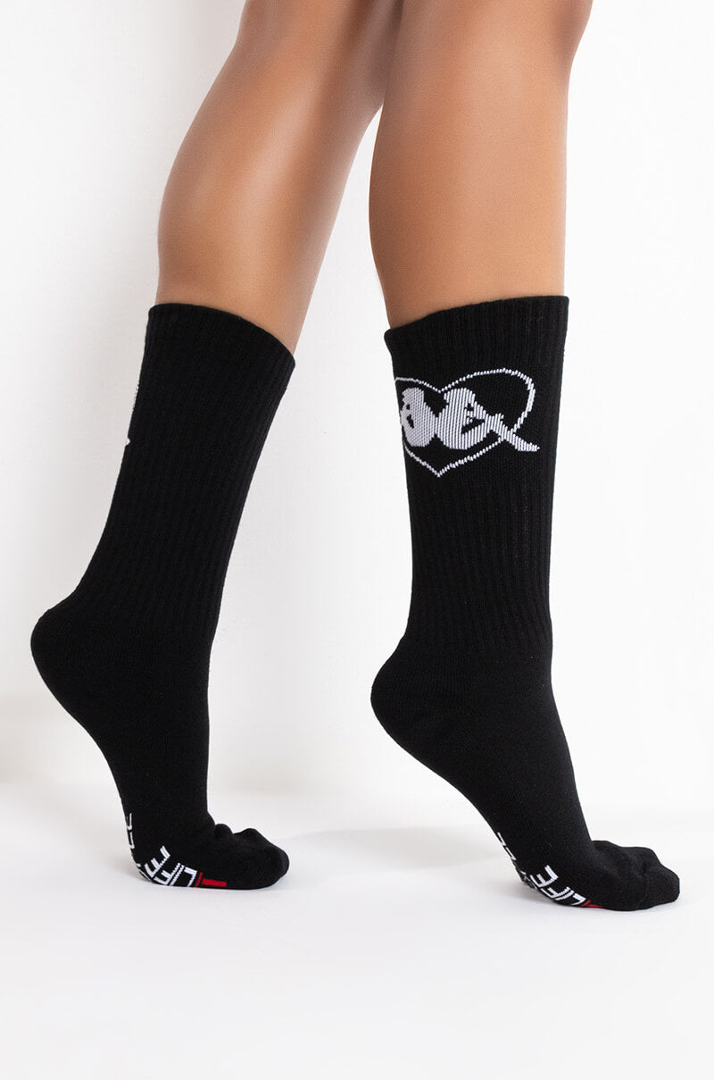 A person is wearing KAPPA ENDLESS LOVE ANKLE SOCKS with white text and a heart design near the top. They are standing on their toes against a plain white background. 2