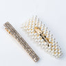 Two hair clips from the LADYLIKE HAIR CLIP SET displayed on a white surface. The first clip is a rectangular bar covered with small, shiny rhinestones. The second clip is a larger, teardrop-shaped barrette adorned with small white pearls. Both clips have metallic backings.