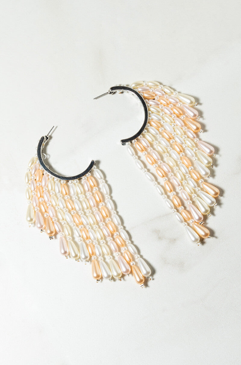 The LET IS GO PEARL EAR CUFFS laid out flat on a light surface. They feature multiple rows of dangling teardrop-shaped pearls in various shades of white, cream, and light pink, attached to a metallic base.
