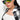 A person with long dark hair wears oversized OCULOS HOLOGRAM AB STONE SUNGLASS, large hoop earrings, a white crop top, and a black-and-white checkered shirt over it. The individual stands against a plain white background.