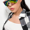 A person with long dark hair wears oversized OCULOS HOLOGRAM AB STONE SUNGLASS, large hoop earrings, a white crop top, and a black-and-white checkered shirt over it. The individual stands against a plain white background.