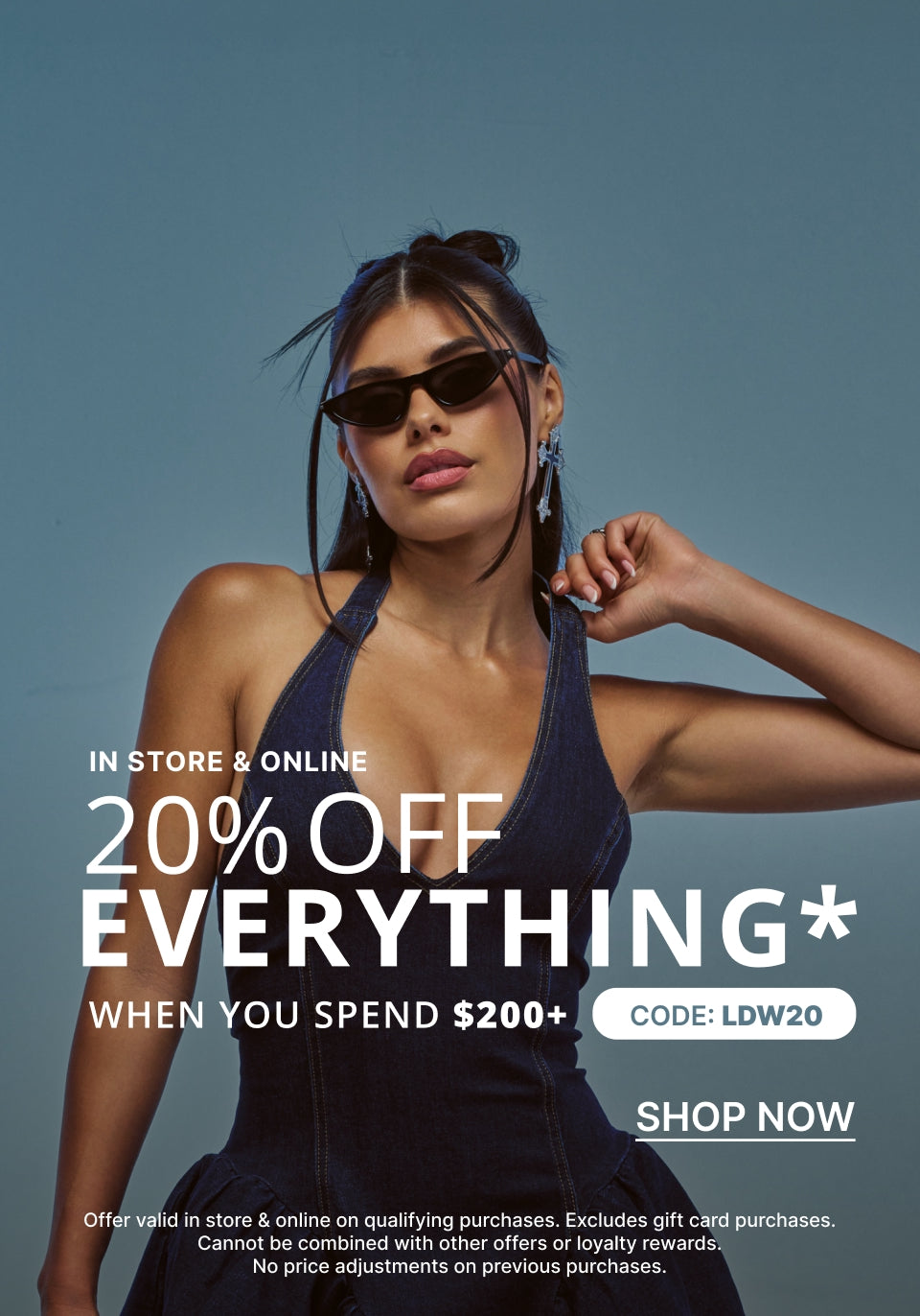 A promotional fashion ad featuring a woman wearing dark sunglasses and a dark halter top against a muted blue-gray background, with large text reading '20% OFF EVERYTHING WHEN YOU SPEND $200+' and 'SHOP NOW'.
