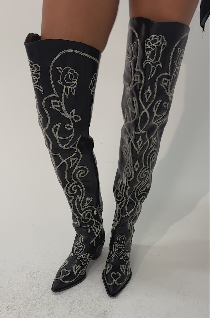 Video of woman modeling the AZALEA WANG KESS BLACK WESTERN THIGH HIGH CHUNKY BOOT with white embroidery, standing against a plain light background.