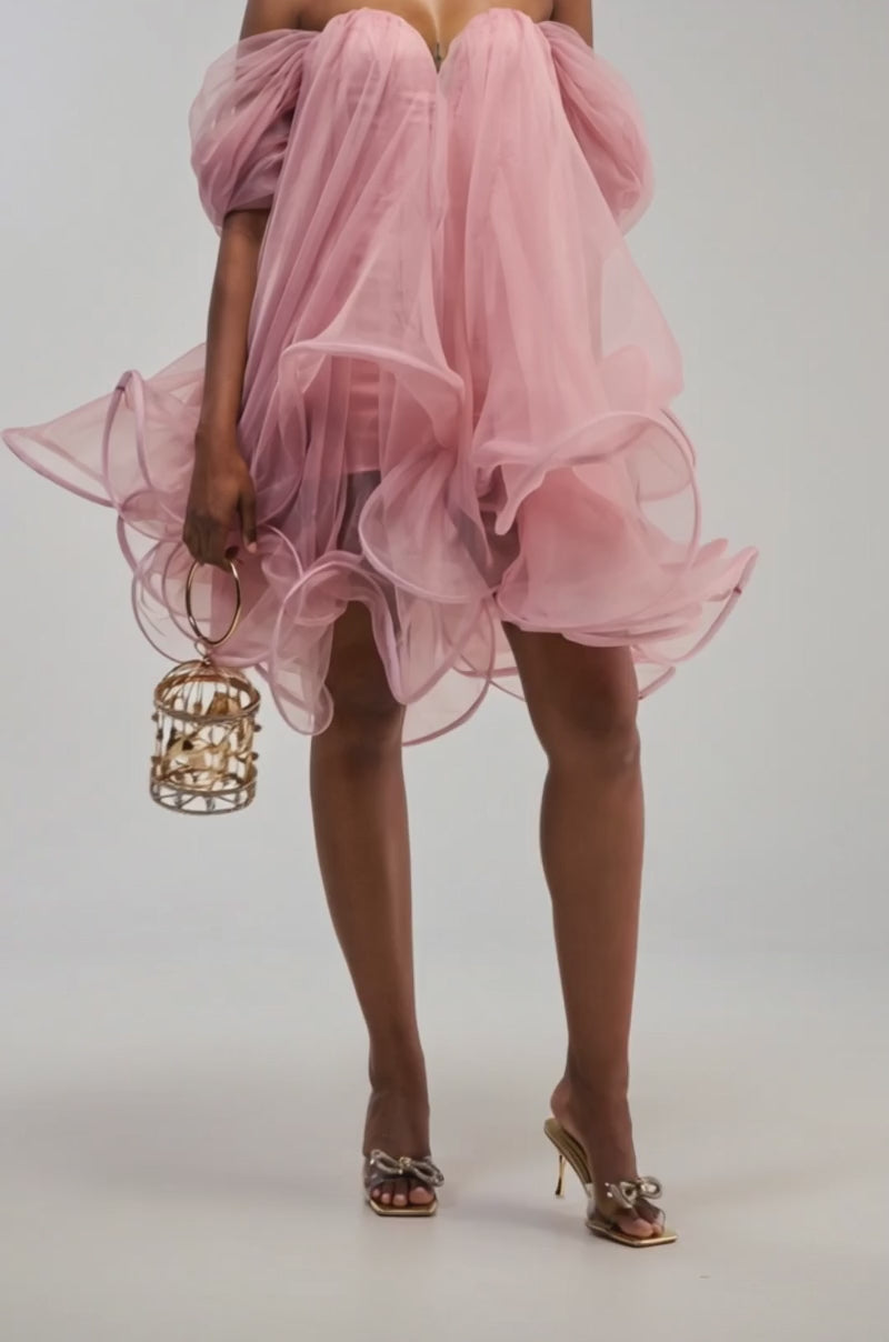 Video of a woman modeling the DANCE WITH ME CHIFFON MINI DRESS IN MAUVE, a voluminous, off-the-shoulder dress featuring pastel mauve chiffon, ruffled edges, and sculptural boning.