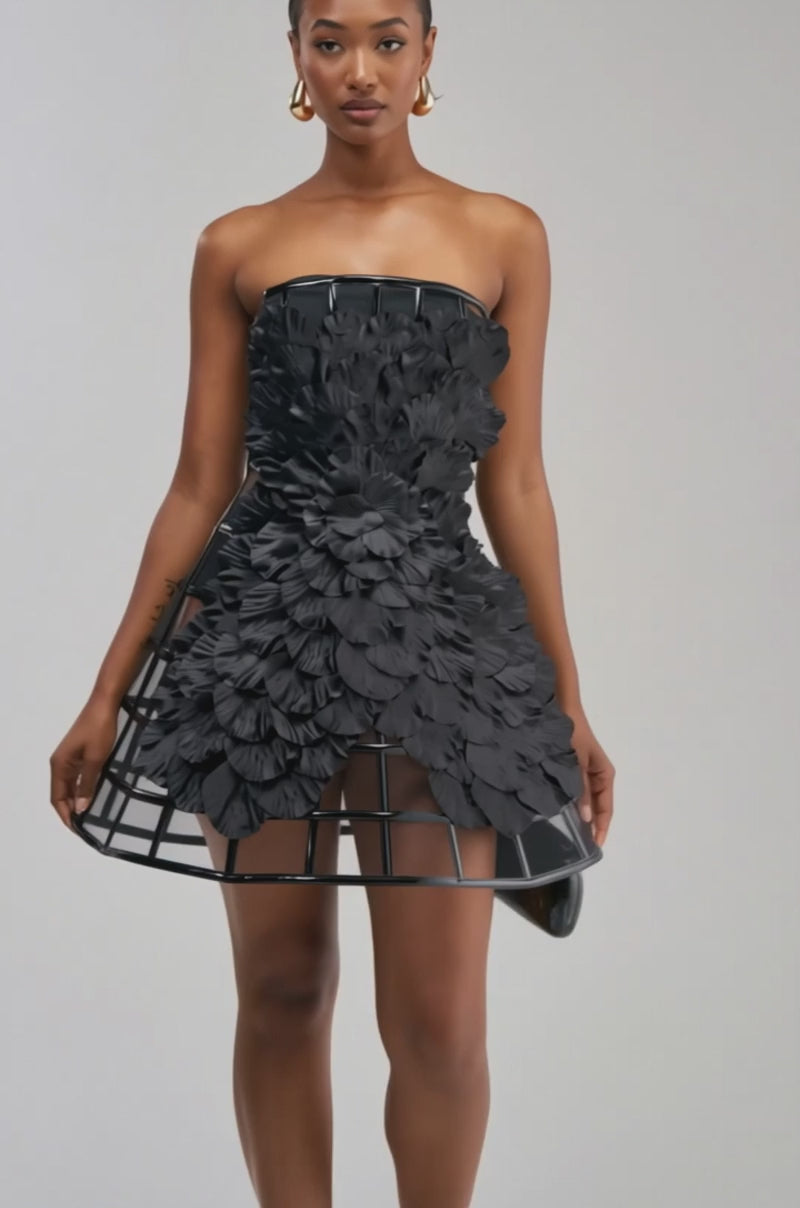 Video of a woman modeling the FULL BLOOM CAGE DRESS IN BLACK—a strapless mini dress featuring 3D floral details and a structured, cage-like skirt.
