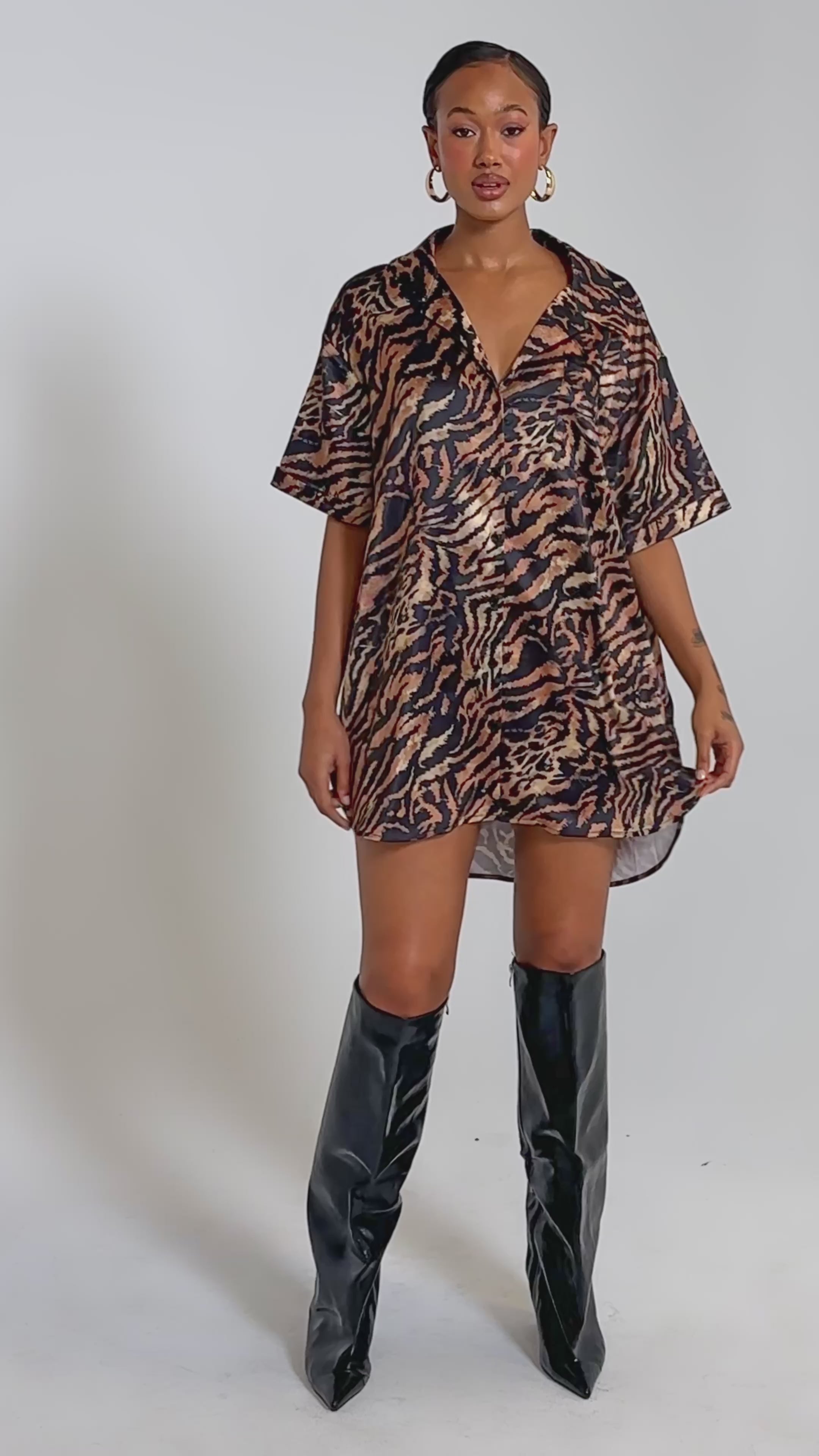 A video of a woman in the DON'T MAKE A SOUND PRINTED MINI DRESS IN TIGER, a loose short tiger print dress with a V-neck, short sleeves, and black lace trim. 