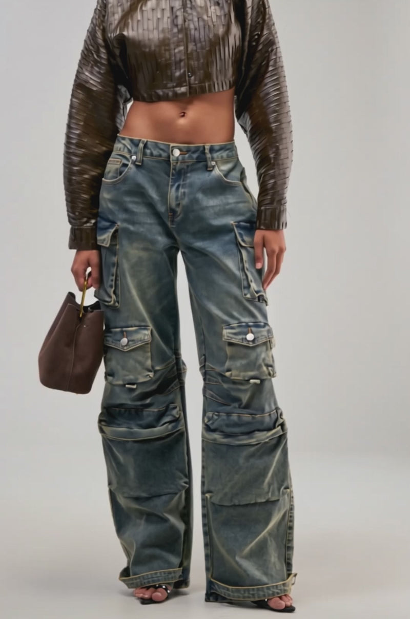 Video of a woman modeling the VINTAGE LOVER CARGO DENIM, featuring a wide-leg silhouette and multiple pockets, styled with a cropped brown textured jacket and holding a brown handbag.