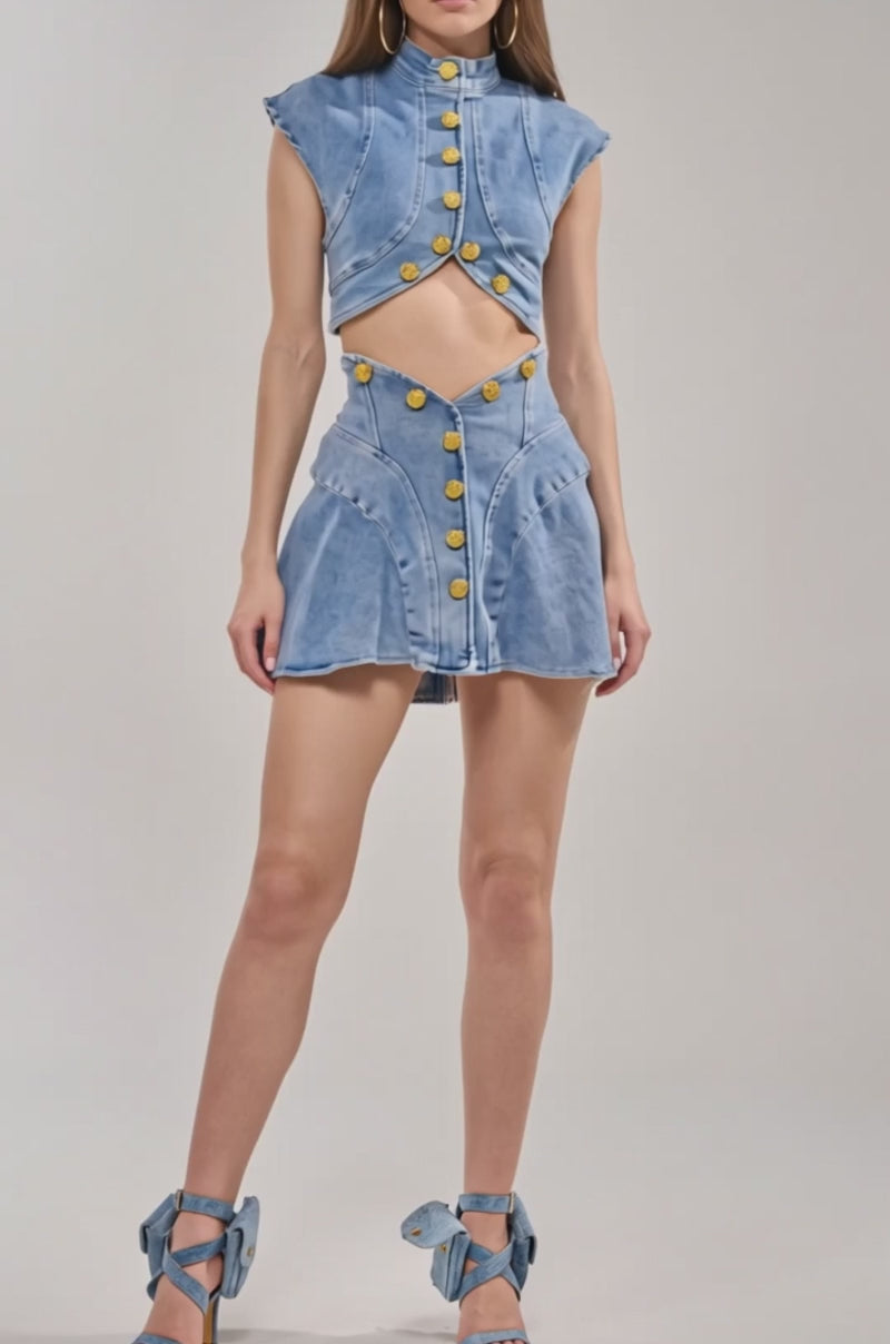 Video of woman modeling the GIVE IT TO ME BABY DENIM BUTTON DOWN—a vintage-inspired, gold button, high-neck denim top with a matching high-waisted skirt.