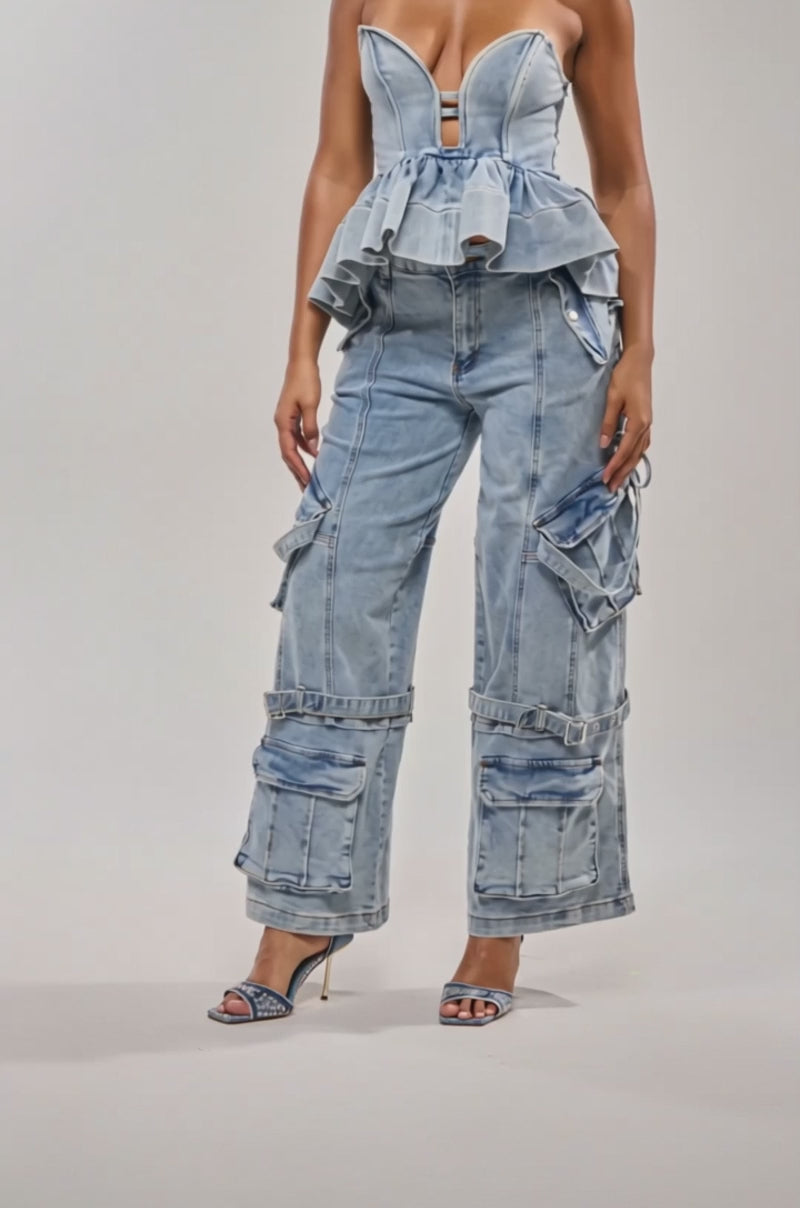 Video of woman modeling the KARA DENIM CARGO PANT—wide-leg, light wash cargo jeans with multiple pockets—paired with a strapless, structured denim peplum top and open-toe heels.