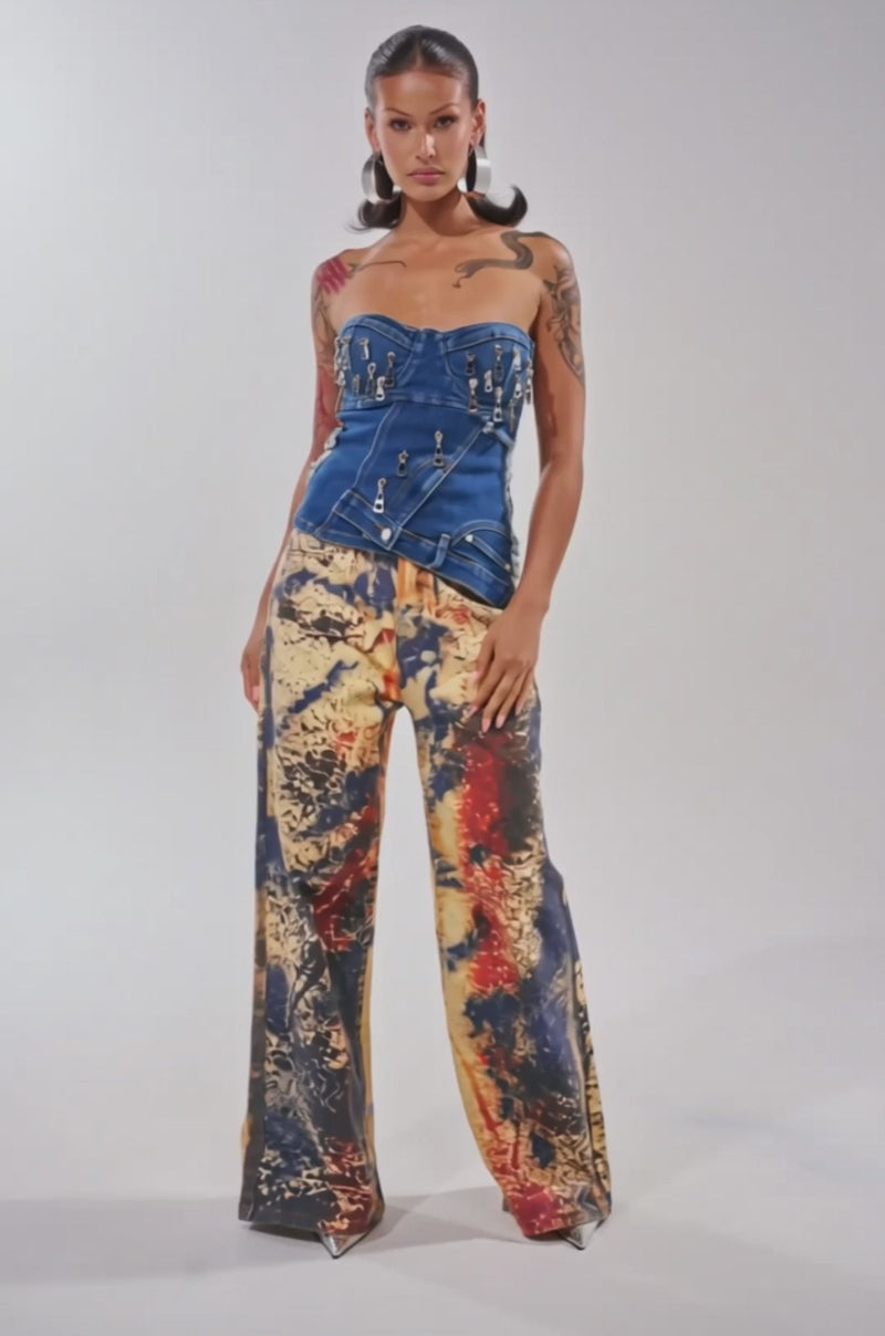 Video of woman modeling the CHAINED OUT CORSET—a strapless indigo denim top with a sweetheart neckline and multiple zippers—paired with a printed skirt, against a plain light background.