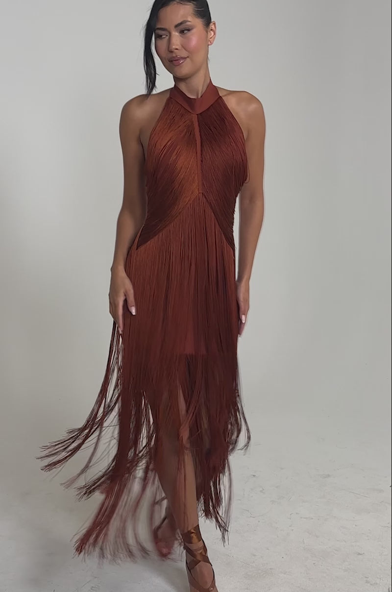 Video of woman modeling the FORGET ME NOT FRINGE MAXI DRESS in rust, pairing it with a small clutch and strappy heels. 