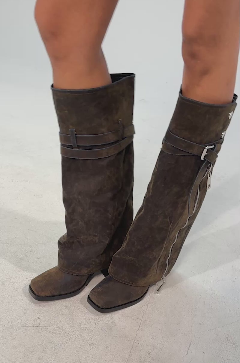 Video of woman modeling the AZALEA WANG EIRA Brown Block Boot with a square toe, featuring slouchy, distressed knee-high design, side zippers, decorative straps and silver buttons