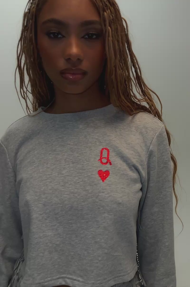 Video of a woman modeling the PLAYING CARDS CROP SWEATSHIRT IN HEATHER GREY, featuring a large Queen of Hearts playing card graphic on the back.