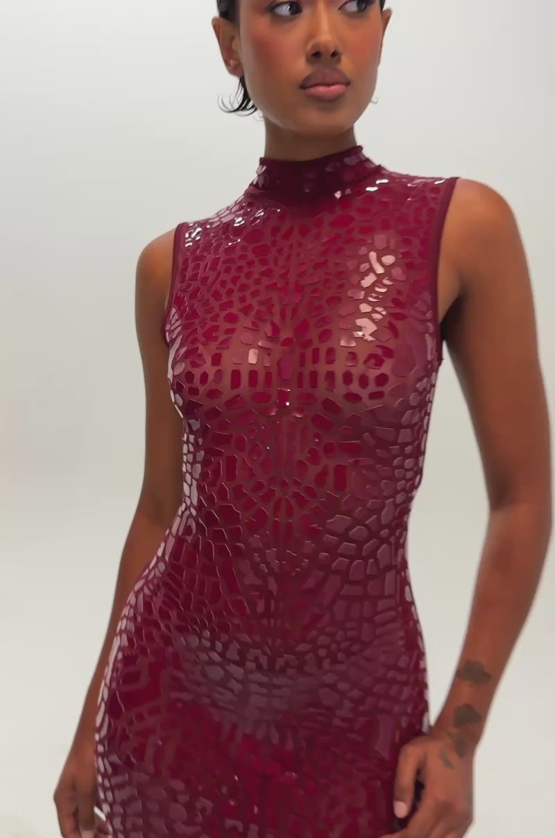 Video of a woman modeling the PAPARAZZI Printed Mesh Maxi Dress in Burgundy—a sleeveless, form-fitting gown featuring a shiny, cracked pattern.