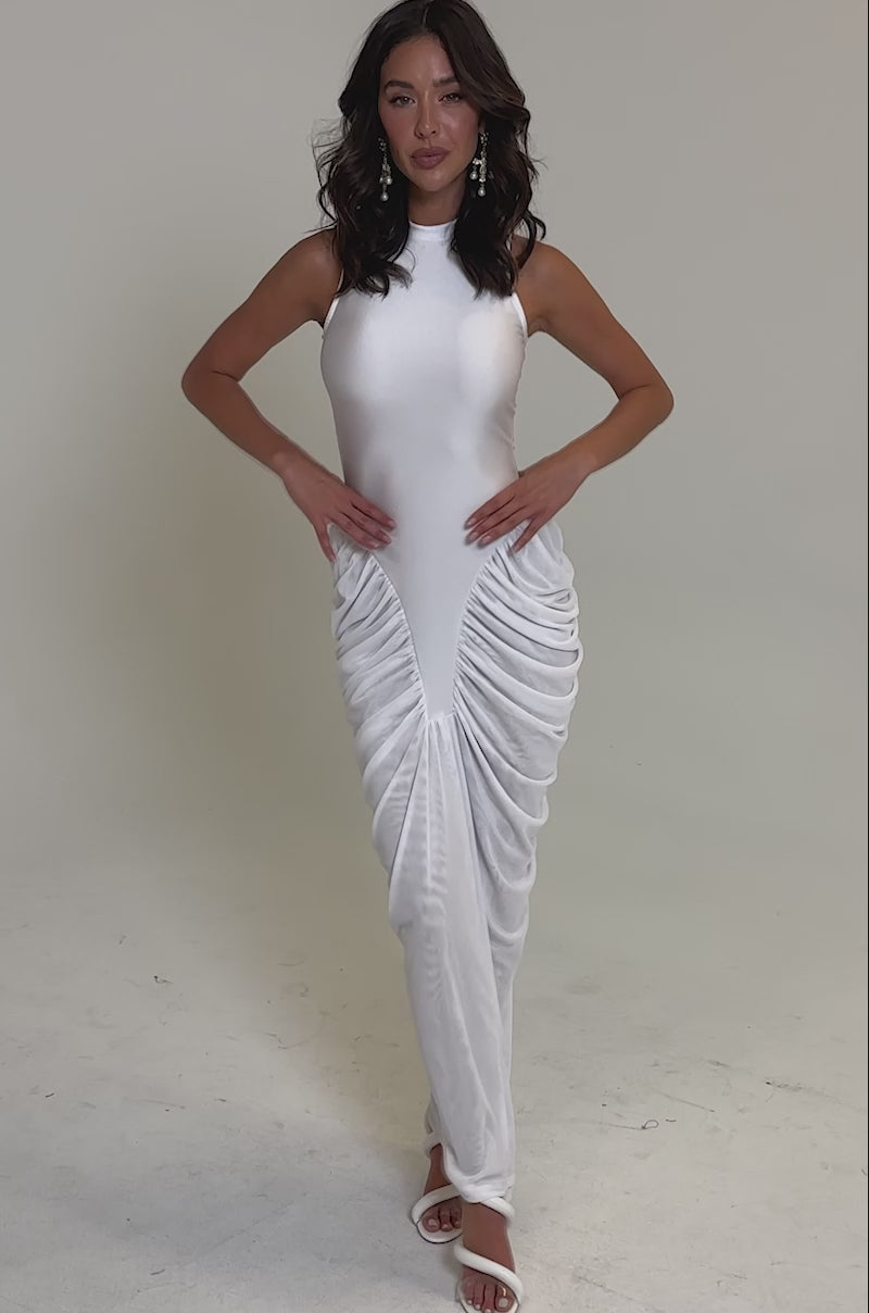 Video of woman modeling the SECOND DATE BODYCON SHINE MAXI DRESS IN WHITE—a sleeveless, high-neck, all-white dress with gathered ruching—paired with white heeled sandals against a plain light background.