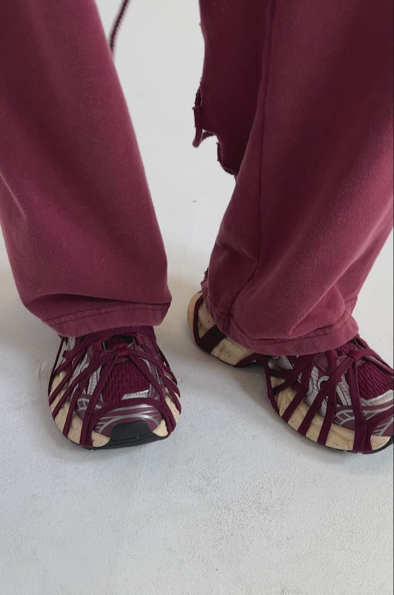 A video of a model wearing AZALEA WANG SELIE BURGUNDY LACE UP SNEAKERS with crisscross straps and beige soles.