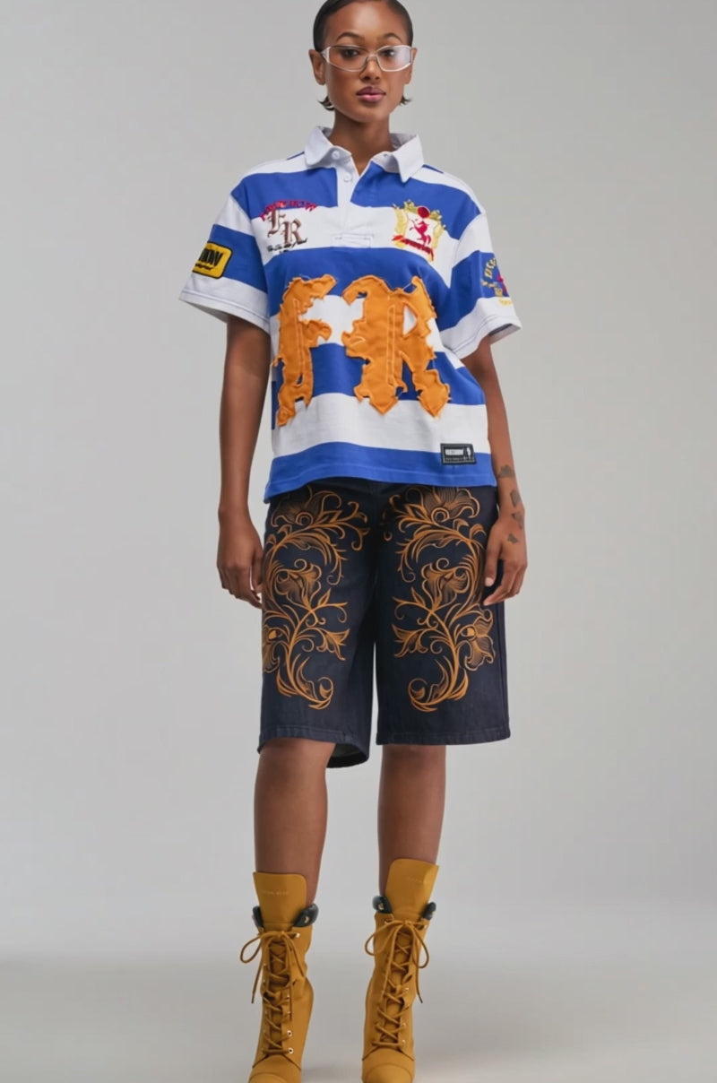 Video of a woman modeling the FIRST ROW ICON STATUS CROPPED STRIPED POLO—a blue and white striped shirt adorned with patches and embroidery for a touch of streetwear flair.
